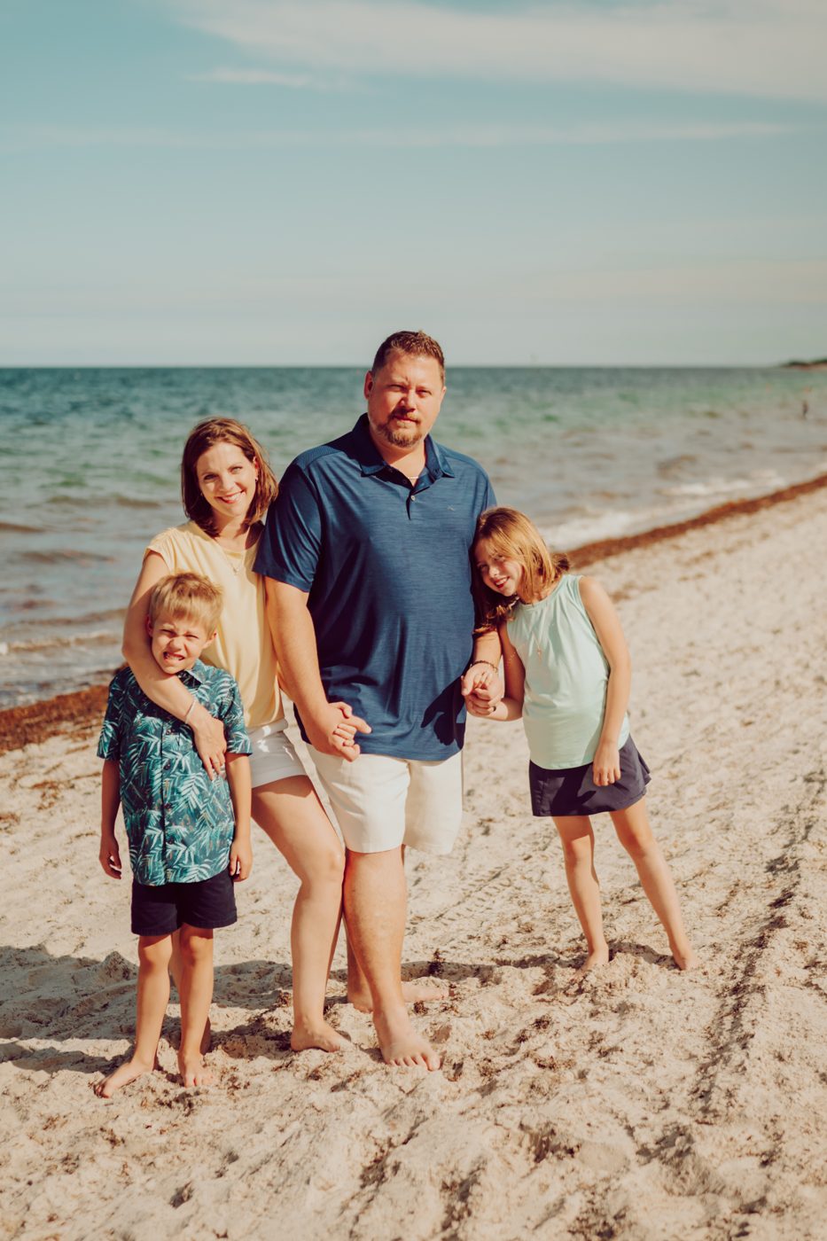 Chris Nelson with his wife and two kids on a beach.